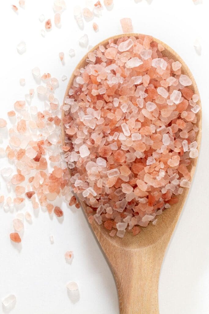 This is a photograph of some pink Himalayan salt on a wooden spoon.