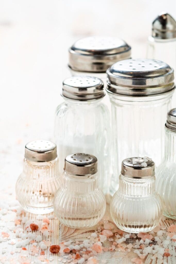 This is a photograph of various salt shakers filled with salt.
