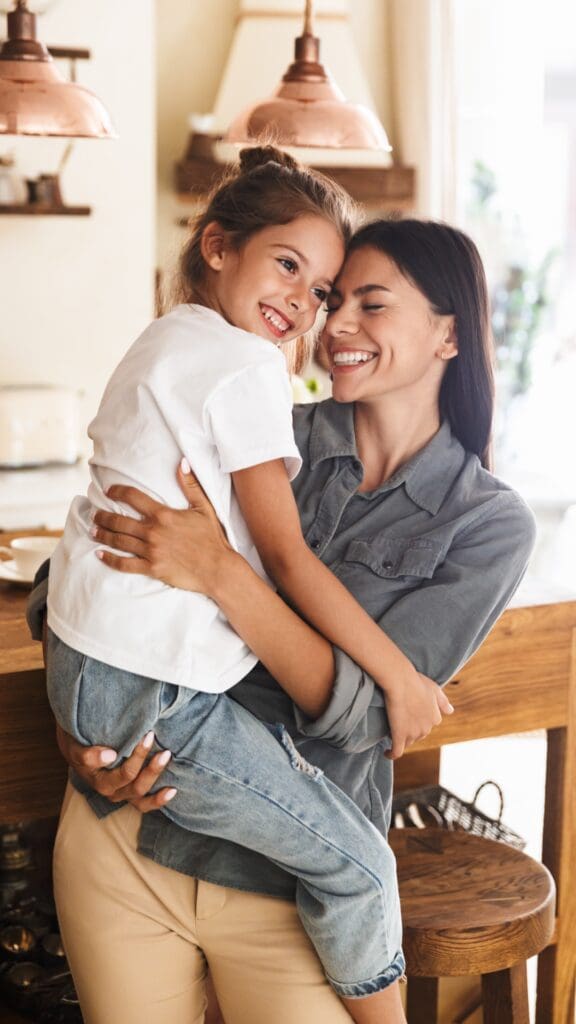 smiling mom holding smiling daughter